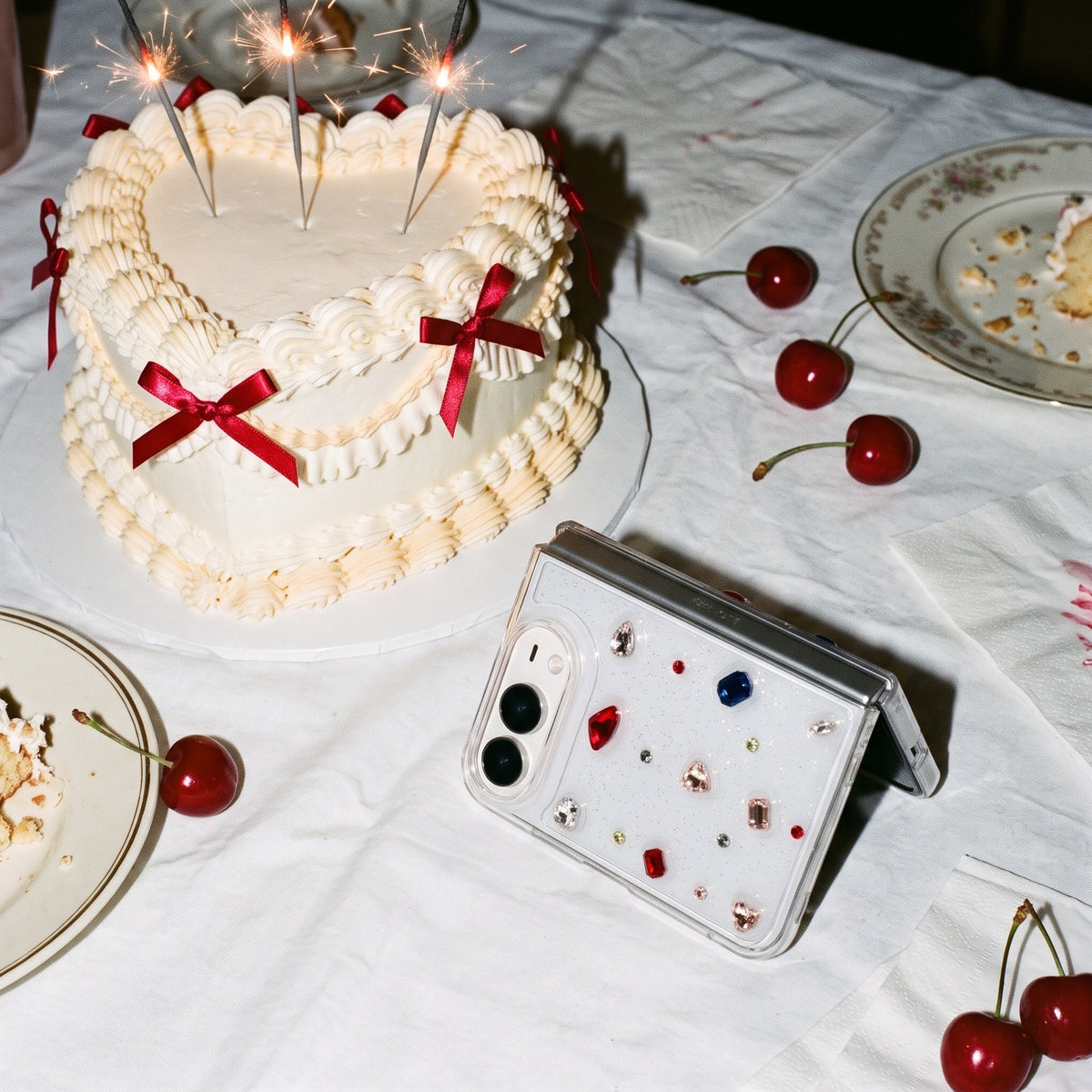 Cute rhinestone iPhone Duo case next to a vintage heart cake with red bows and cherries at a party