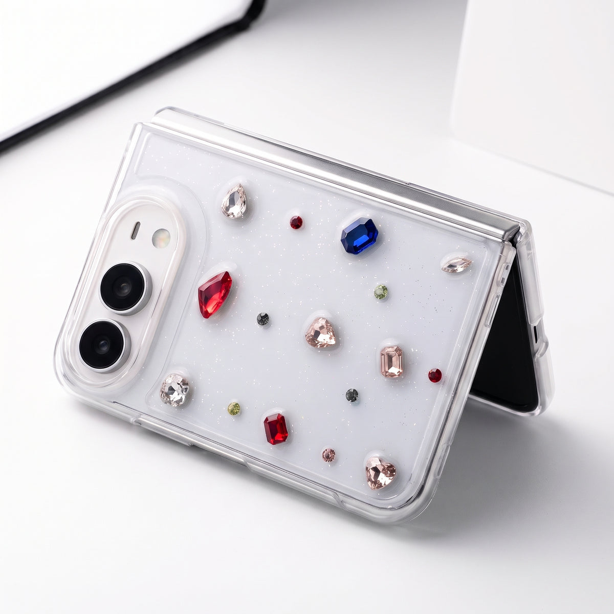 GEM GARDEN glitter rhinestone case on iPhone Duo, folded and standing on a white table