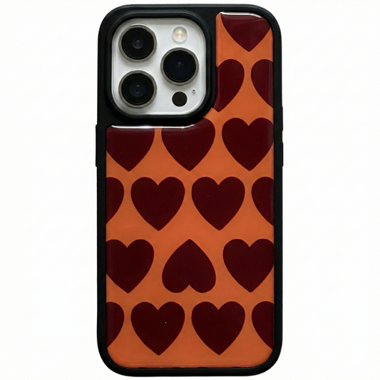 Glossy iPhone case featuring a retro dark red repeating heart pattern on an orange background with a protective black rubber bumper.